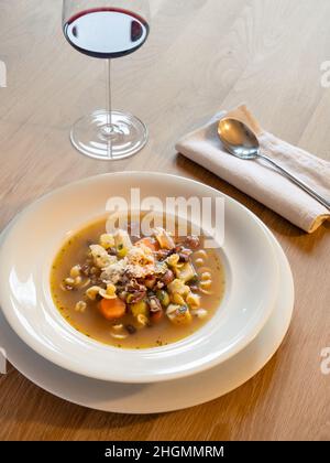 Soupe de légumes italiens minestrone dans une assiette blanche avec cuillère et verre à vin Banque D'Images