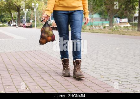 Une femme porte un sac réticable, les jambes en gros plan. Banque D'Images