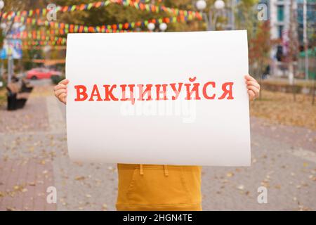Une femme possède une affiche avec du texte, traduit de l'ukrainien: Se faire vacciner Banque D'Images