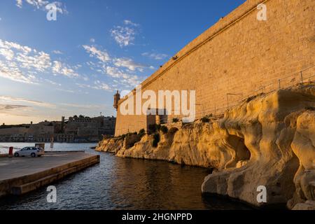 Mur du fort Saint-Ange au coucher du soleil, fortification en bord de mer à Birgu, Malte. Banque D'Images