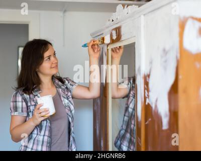 Femme fait des réparations dans l'appartement et peint placard Banque D'Images