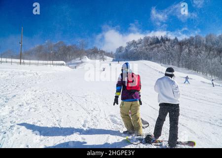 Deux snowboarders surfent en montagne. Snowboarders profitant des activités de loisirs en plein air. Groupe d'amis appréciant la saison d'hiver. Banque D'Images