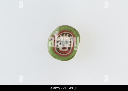 Inlay / perle blanc avec face 100 BC–100 AD période Ptoléméenne–période romaine Une technique de mosaïque de verre a permis de créer des multiples d'une image: Une composition figurale ou design a été faite en regroupant des cannes en verre coloré, qui ont ensuite été tirées dans une longue barre.La barre a ensuite été sectionnée à angle droit, probablement en frappant la barre avec les outils appropriés, pour produire de petits carreaux incrusts.Le carreau serait alors lissé et poli sur la face destinée à apparaître vers l'extérieur.Incrustation / cordon avec face.100 BC–100 AD.Verre.Période Ptolemaic–période romaine.De l'Égypte Banque D'Images