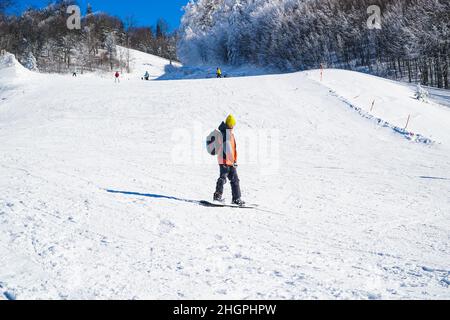 Homme dans des vêtements chauds snowboard freestyle de descente.Sports d'hiver.Sports extrêmes en hiver.Snowboardeur pour les sports extrêmes. Banque D'Images