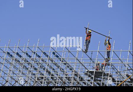 On voit des ouvriers travailler sur un échafaudage sur le chantier de construction de routes côtières à Mumbai.Le projet de route côtière est une autoroute à huit voies qui reliera la partie sud de la ville à l'extrémité nord Banque D'Images