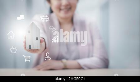 Femme d'affaires et mini maison en bois modèle et cubes en bois d'affaires de modèle sur table en bois, planification achat immobilier, planification pour acheter la propriété.Accueil Banque D'Images