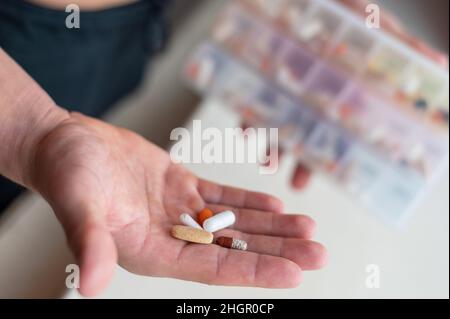 Gros plan d'une paume mâle avec des pilules.Un homme prend une dose quotidienne de vitamines et de suppléments nutritionnels d'une boîte quotidienne de pilules. Banque D'Images