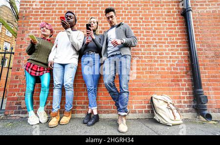 Des amis urbains multiculturels utilisant des smartphones mobiles au mur à Shoreditch London - technologie addiction Life style concept avec les gars et les filles ennuyés Banque D'Images