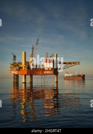 forage de plate-forme d'accrochage en mer avec beau ciel nuageux et beau reflet en mer pendant le coucher du soleil Banque D'Images