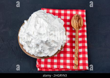 Crème en poudre (crème en poudre) crème fouettée dans une assiette sur parquet.Faire cuire de la crème de beurre dans la cuisine. Banque D'Images