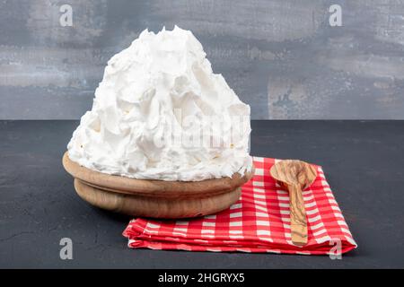 Crème en poudre (crème en poudre) crème fouettée dans une assiette sur parquet.Faire cuire de la crème de beurre dans la cuisine. Banque D'Images