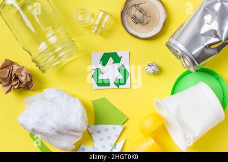 Clean trash to recycle - metal, plastic paper and glass. Recycling concept on yellow. Banque D'Images