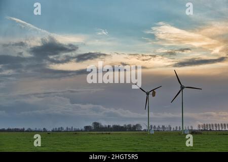 Deux éoliennes dans un pâturage, dans la province agricole néerlandaise de Groningen, ont silhoueté contre le ciel de la soirée Banque D'Images