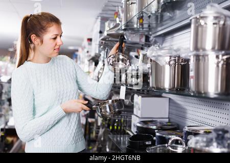 La jeune femme cherche un stewpot moderne pour sa cuisine Banque D'Images