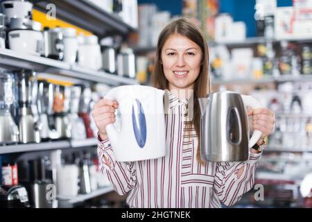 Femme de vente adulte proposant une bouilloire électrique Banque D'Images