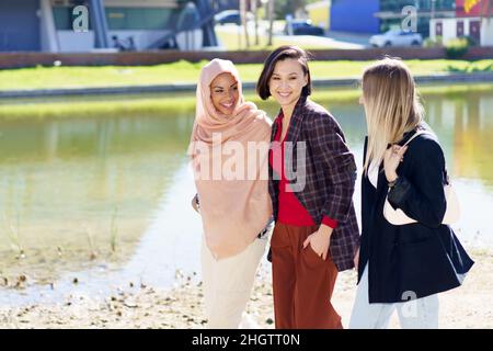 Contenu jeunes femmes multiethniques parlant en se promenant sur les remblais de la ville Banque D'Images