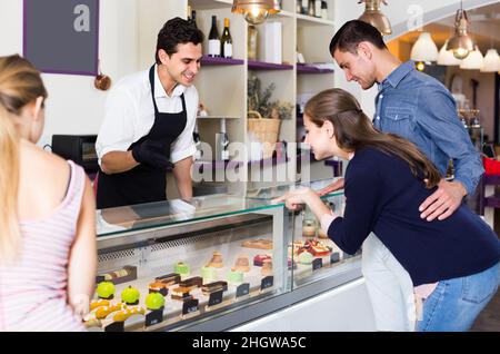 Couple avec femme ami sont de choisir de délicieux gâteaux de la vitrine Banque D'Images