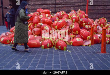 Londres, Royaume-Uni 22nd janvier 2022.Une femme passe devant une pile de vieilles lanternes abandonnées dans Chinatown alors que de nouvelles lanternes rouges étaient installées avant le nouvel an chinois.Credit: Vuk Valcic / Alamy Live News Banque D'Images