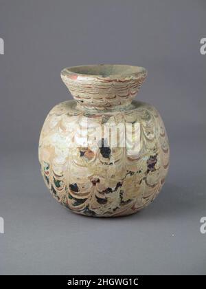 Bocal en verre avec sentiers marrés 5th Century A.D. ou plus tard romain, Syro-palestinien violet translucide; sentiers en rouge et blanc brunâtre opaque.épais, rebord extérieur, avec un bord légèrement biseauté; col en forme d'entonnoir; épaule enfoncée; corps globulaire; coup de pied dans le fond,Avec des traces de pontil-pad.deux sentiers marrés enroulés dans une spirale de bord en bas; sur le corps et le cou, outillés dans des festons suspendus avec dix-sept coups d'outillage vers le haut; autour du fond, outillés vers le bas, formant un motif très confus.intact; des bulles d'épingle sur la surface;épaisse couche d'altération et d'iridescenence brun crémeux couvrant la majeure partie de la dbo Banque D'Images