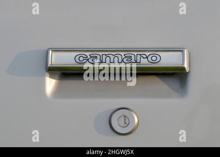 Emblème Camaro sur la poignée de porte d'une Camaro Z28 1981 de Chevrolet argentée au crépuscule. Banque D'Images