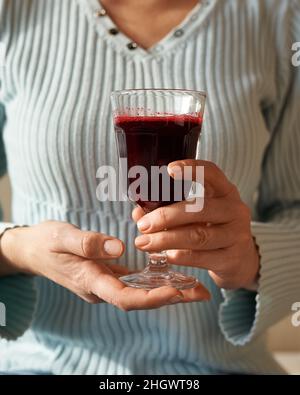 Femme tenant un verre de jus de betterave rouge fraîchement pressé Banque D'Images