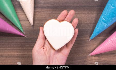 Cookie en forme de coeur blanc pour la fête des mères, la fête des femmes ou la fête de la Saint-Valentin sur fond de bois. Copier l'espace Banque D'Images