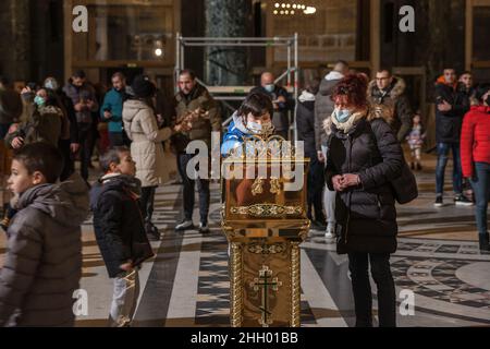 Photo d'une famille blanche caucasienne priant en portant un masque de Noël dans l'église orthodoxe du temple de Saint Sava tout en portant un protectiv Banque D'Images