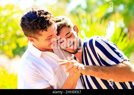 Un couple gay heureux passe du temps ensemble dans une journée ensoleillée dans un parc verdoyant Banque D'Images