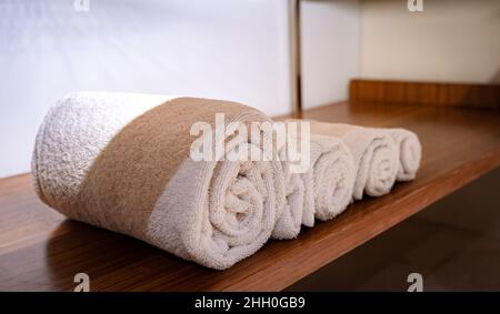 Un ensemble de serviettes de bain propres roulées sur une plate-forme en bois. Banque D'Images