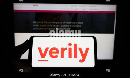 Personne tenant un smartphone avec le logo de la société de recherche américaine Verily Life Sciences LLC sur l'écran devant le site Web.Mise au point sur l'affichage du téléphone. Banque D'Images