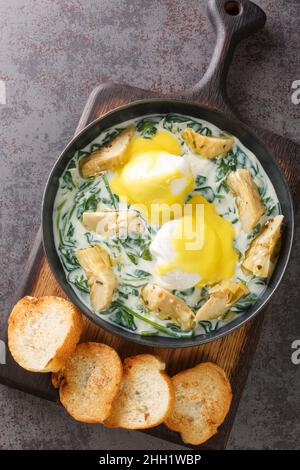 Les œufs traditionnels de la Nouvelle-Orléans, sardou, crème d'épinards, artichauts, œufs pochés et sauce hollandaise, se trouvent dans l'assiette de la table.Vertical à Banque D'Images