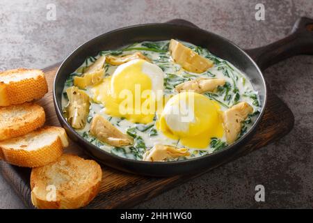 Œufs : recette de brunch Sardou de la Nouvelle-Orléans préparée avec des œufs pochés, servi de l'artichaut et des épinards crémeux et nappés d'une sauce hollandaise en gros plan Banque D'Images