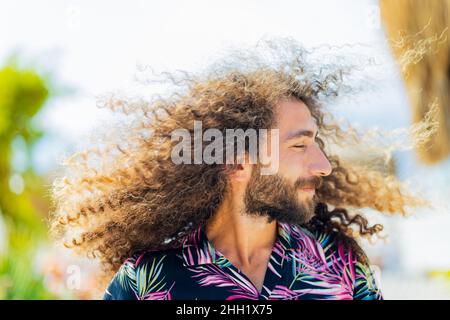 Un homme barbu et à tête bouclés d'afro vole en plein air Banque D'Images