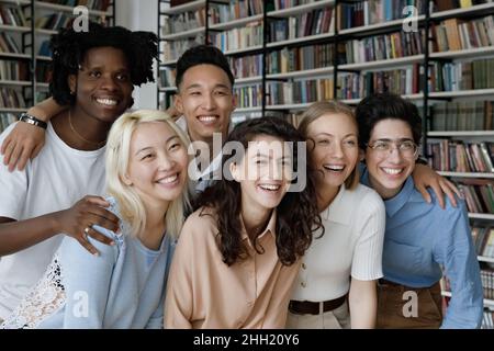 Groupe diversifié de filles et de garçons étudiant posant dans la bibliothèque Banque D'Images