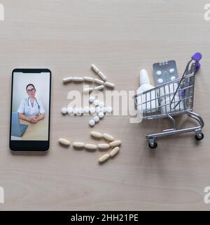 Une femme sympathique médecin sur l'écran d'un smartphone prescrit un traitement.Médecine en ligne.Mini chariot avec pilules.Consultation à distance.Application mobile Banque D'Images