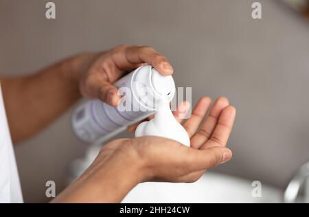 Homme méconnaissable appliquant de la mousse à raser sur la main, debout dans la salle de bain et se préparant au rasage, gros plan Banque D'Images