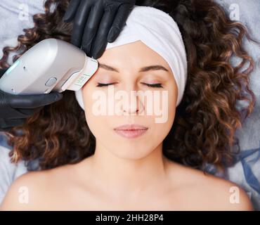 Visage de fille subissant un facilift non chirurgical pour restaurer les contours clairs de la face ovale.Médecin utilisant l'échographie qui agit sur le système aponévrotique musculaire superficiel, favorisant le rajeunissement. Banque D'Images