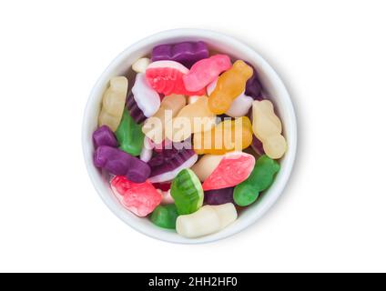 Divers bonbons à la gomme multicolores dans un bol en céramique blanc sur fond blanc.Vue de dessus. Banque D'Images