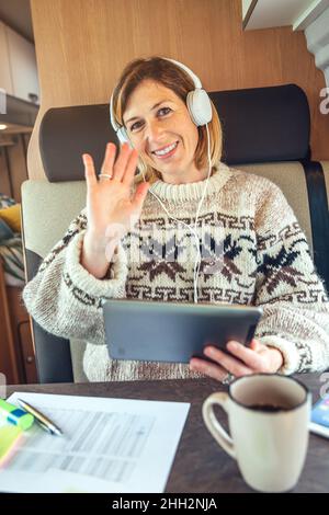 Femme agitant en regardant la caméra lors d'un appel vidéo depuis son camion Banque D'Images