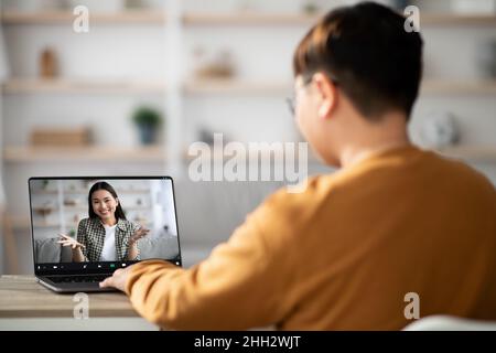 Vue arrière de l'adolescent ayant un appel vidéo avec une femme asiatique Banque D'Images