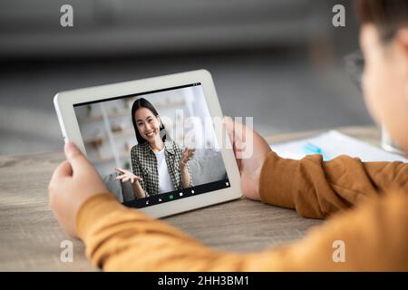 Enfant méconnaissable ayant un chat vidéo avec un tuteur, à l'aide d'une tablette numérique Banque D'Images