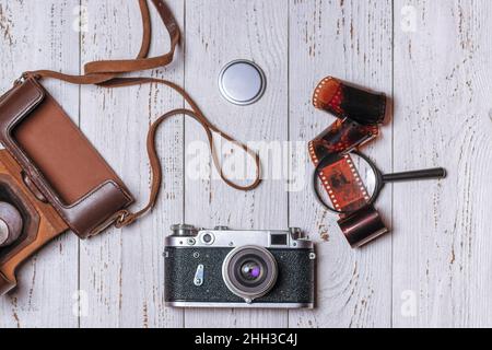 Ancienne caméra rétro avec étui en cuir, loupe et film sur tableaux blancs.Vue de dessus. Banque D'Images