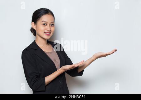 Jeune femme d'affaires asiatique souriante confiante pointant du doigt vers des directions différentes Banque D'Images