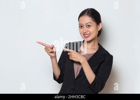 Jeune femme d'affaires asiatique souriante confiante pointant du doigt vers des directions différentes Banque D'Images