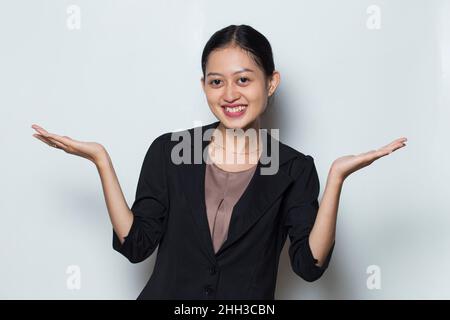 Jeune femme d'affaires asiatique souriante confiante pointant du doigt vers des directions différentes Banque D'Images