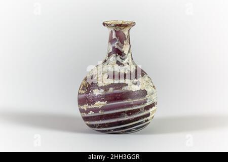 Flacon de parfum en verre 1st Century A.D. Roman violet translucide, avec des traces blanches opaques.rebord arrondi et partiellement plié; bouche torchère; col cylindrique, extensible vers le bas; corps globulaire;Fond concave.motif en mosaïque rayé de la double traînée appliquée enroulée autour d'une spirale sur un sol violet.intact; piqûres, morcellement, iridescenence, et blanchâtre.Flacon de parfum en verre.Romain.1st siècle A.D..Verre ; soufflé et traîné.Début de l'Impériale.Verre Banque D'Images