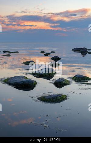 Heure bleue après le coucher du soleil sur la mer Baltique rocheuse coût.Petites pierres et gros rochers dans la mer.Exposition longue Banque D'Images