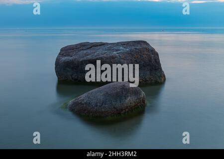 Heure bleue après le coucher du soleil sur la mer Baltique rocheuse coût.Petites pierres et gros rochers dans la mer.Exposition longue Banque D'Images