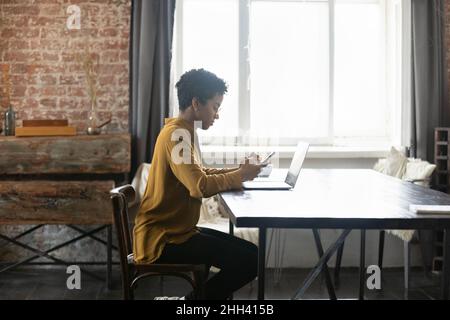 Femme d'affaires afro-américaine sérieuse utilisant des appareils numériques sur le lieu de travail Banque D'Images