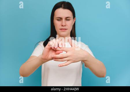 Gros plan des femmes malades souffrant de douleurs articulaires de la main et du doigt avec rougeur, modèle sur fond bleu.Les causes de douleur incluent la polyarthrite rhumatoïde, c Banque D'Images